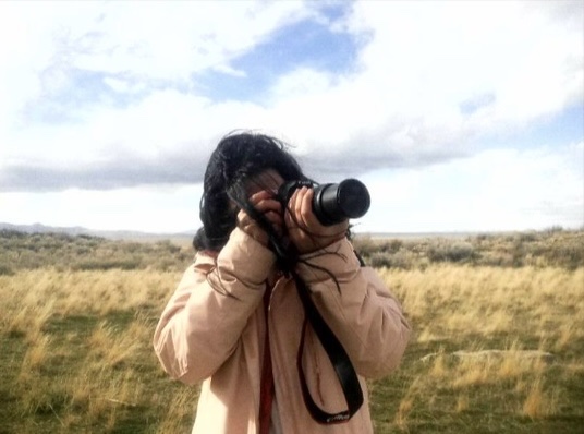 Daniela Videa taking a photo with a camera in an open field