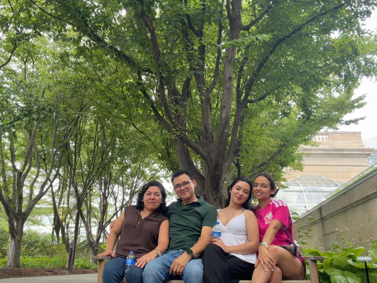 Daniela Videa with her parents and sister on a bench under the trees