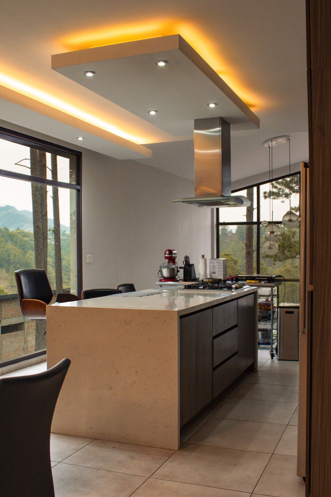 Kitchen island under a glowing ceiling panel, forest view